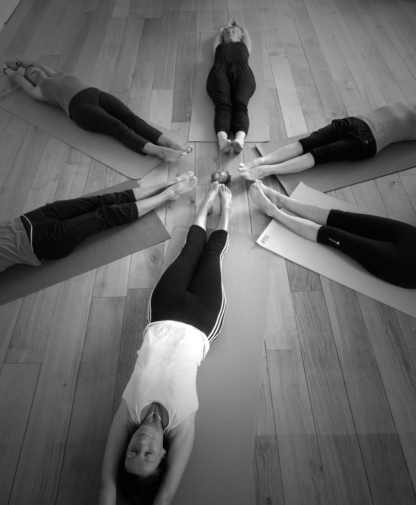 Groupe allongé en cercle, jambes levées et pieds joints au centre