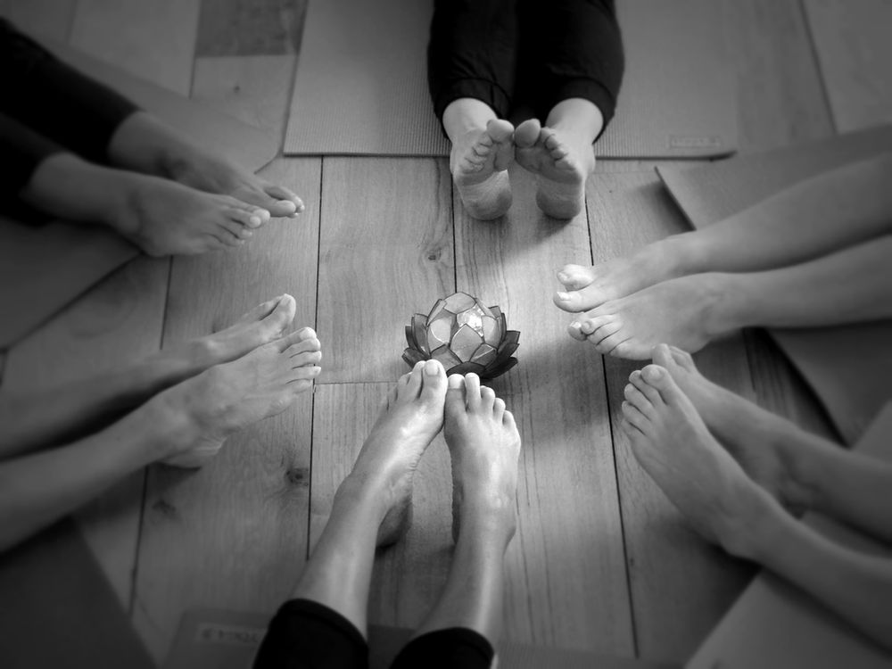Mains et pieds de plusieurs pratiquants réunis en cercle autour d'une fleur